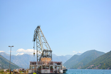 Crane on a ship crane in the industrial port in Montenegro with mountains in the background, summer...
