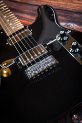 Fototapeta na wymiar Black electric guitar on old wooden background. Close-up