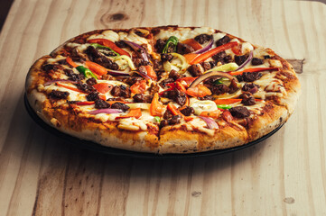 Homemade Baked chicken cheese pizza on a plate on a wooden tabletop, sliced and ready to serve in hot.