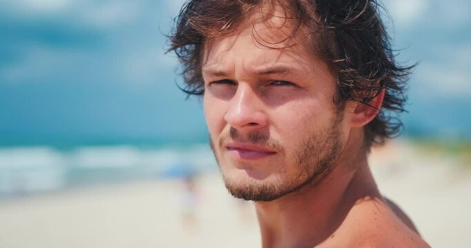 Young man's portrait. Close up portrait of the young Brazilian surfer on the beach. Hand held camera