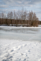 Earrly spring landscape of melting ice on frozen lake surface at sunny day