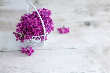 Bouquet of lilacs in a basket on a light wooden background