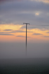 Strommast im Nebel bei Sonnenuntergang bei Schweinfurt