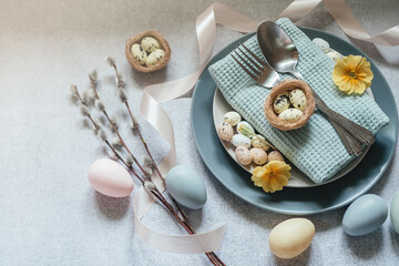 Easter minimal flat lay - Easter eggs, willow catkin branches, bird's nest on light gray background with copy space