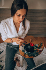 Beautiful talented female artist painting at her home.