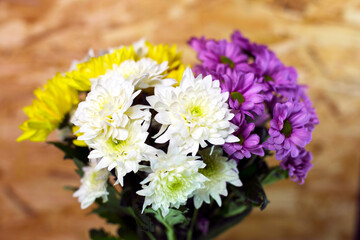 Spring flowers. Bouquet of yellow, purple and white chrysanthemums on a wooden background. Close-up, top view. Spring bouquet. Happy International Women's Day