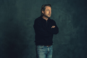 Man with stubble beard in black woolen sweater against grey wall