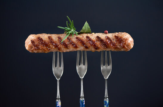 Close up of long grilled kebab on tree forks. Chevapi or chevapchici or kebapche. Copy space poster cobcept.