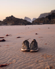 buty pozostawione na dzikiej plaży o zachodzie słońca