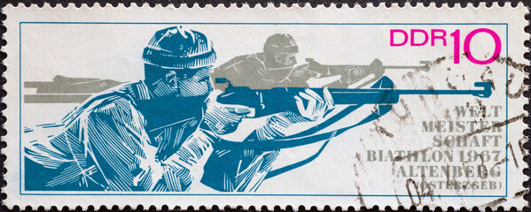 GERMANY, DDR - CIRCA 1967 : a postage stamp from Germany, GDR showing two athletes in prone shooting. Biathlon World Championships, Altenberg