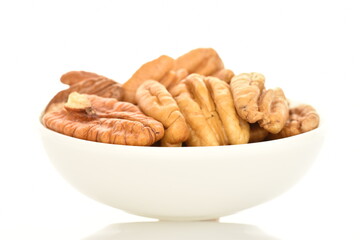Several ripe peeled pecans in a white ceramic saucer, close-up, isolated on white.