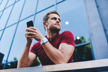 Happy man using smartphone near modern building