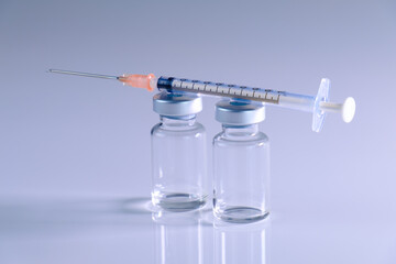 Impfung: Spritze / Injektionsnadel und zwei leere Impf-Ampullen auf neutralen weißen Hintergrund...