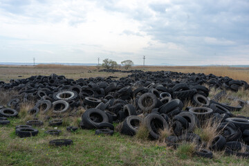 world problem of environmental pollution, huge mountains of discarded car tires near the lake in...