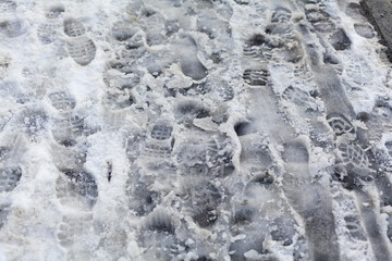 slippery sidewalk in winter covered with slush full of footprints