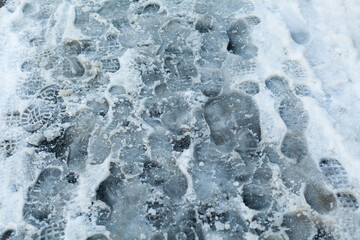 slippery sidewalk in winter covered with slush full of footprints