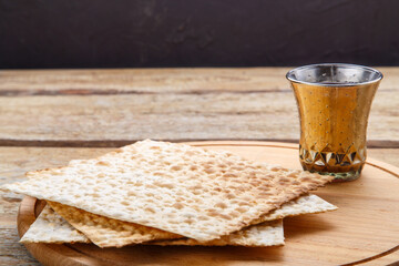 On a round wooden board matzah and a glass of kiddush wine.