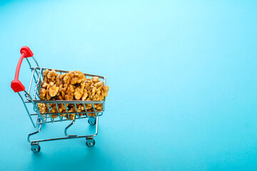 Food cart filled with peeled walnuts on a blue background. Copy space.
