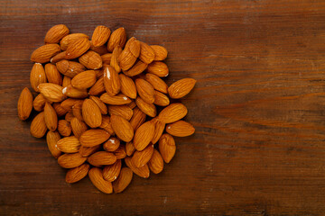 Almond nuts are sprinkled on a dark wooden table.