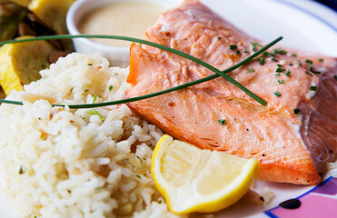 Fresh, healthy salmon fillet and rice pilaf garnished with lemon and scallion