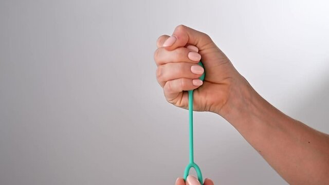 Faceless woman demonstrates a vaginal ball. Girl squeezes a kegel trainer with her hand for training pelvic floor muscles on a white background.