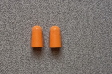 two of red plastic earplugs on a gray table