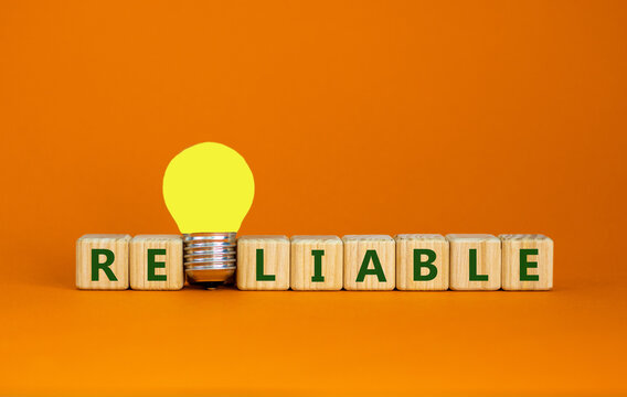 Reliable symbol. Wooden cubes with the word reliable. Yellow light bulb. Beautiful orange background, copy space. Business and reliable concept.