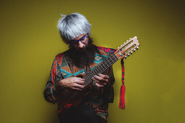 Close-up image of serious brutal bearded man on yellow background playing guitar en the hand