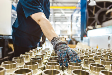 male worker checks many metal pipe couplings in a pipe factory