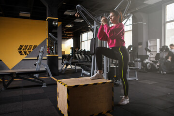 Fototapeta na wymiar Female athlete doing box step ups at the gym, copy space