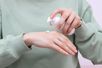 woman is applying nourishing cream to her hand to moisturize her skin, skincare routine theme