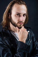 Fototapeta na wymiar bearded man biker in leather jacket with long hair, beard care