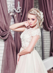 Fototapeta premium Beautiful bride in wedding dress in luxurious apartment. Fashion makeup and hairstyle. Portrait of young gorgeous bride. Wedding. Studio shot.