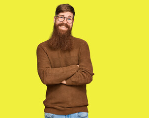 Young irish redhead man wearing casual clothes and glasses happy face smiling with crossed arms looking at the camera. positive person.