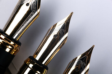 gold plated fountain pens closeup on a grey background