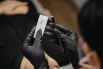 microblading blending needle macro photography. A black-gloved craftsman holds a microblading needle in a package.