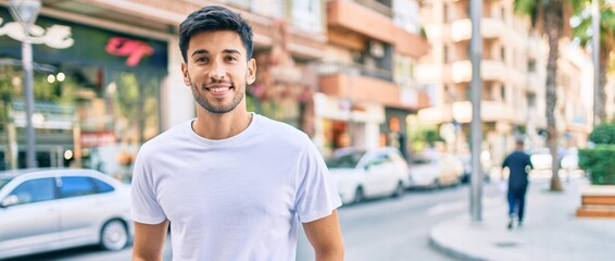 Young latin man smiling happy walking at the city.