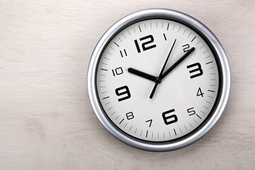 large white clock face with digits on a wooden background closeup