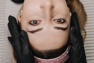 eyebrow microblading. the hands of the master in black gloves hold the maniple on the eyebrow of the model. macro photography