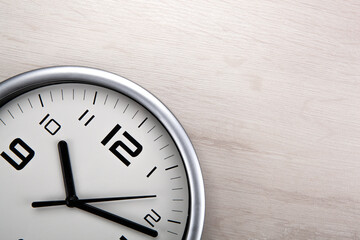 large white clock face with digits on a wooden background closeup