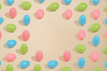 Playful pastel Easter pattern made of pink, green and blue eggs on beige background and copy space. Minimal concept style.
