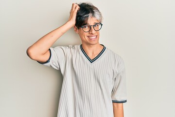 Young hispanic man wearing casual clothes and glasses confuse and wonder about question. uncertain...