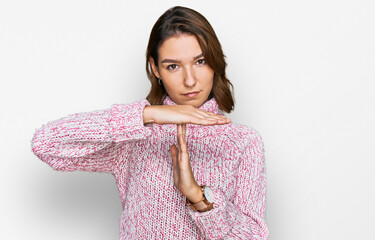 Young caucasian girl wearing wool winter sweater doing time out gesture with hands, frustrated and...