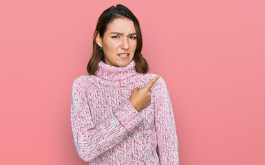 Young caucasian girl wearing wool winter sweater pointing aside worried and nervous with...