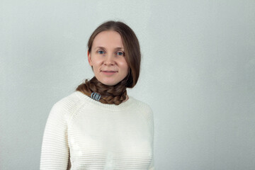 Beautiful caucasian young woman with a long braid around her neck on a gray background