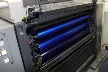 The blue painted roller system of the printing machine in Matbaa. Komori lithrone. selective focus