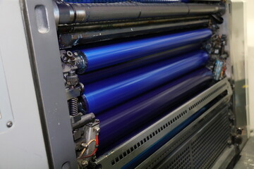 The blue painted roller system of the printing machine in Matbaa. Komori lithrone. selective focus