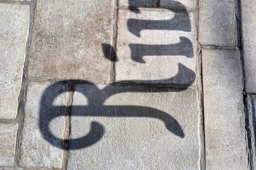 Shadow of Lettering on Textured Stone Pavement