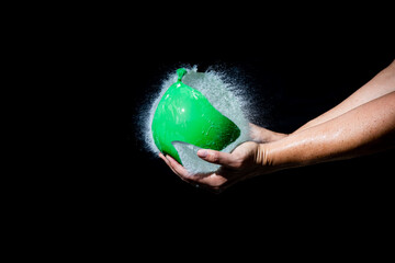 Water balloon bursting in hands