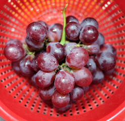 Tasty red grapes in red container, top view, selective focus and soft light .